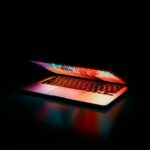 image of a macbook half way shut with a dark background
