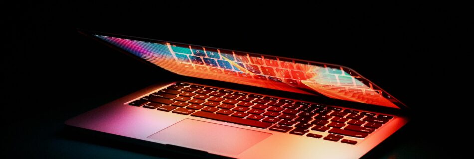 image of a macbook half way shut with a dark background